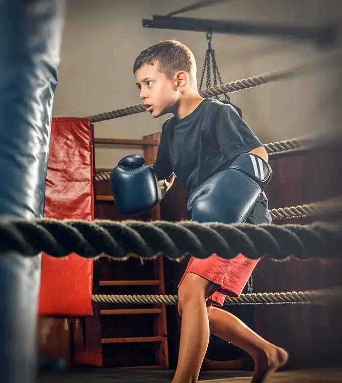 Ein Junge steht vor dem Boxsack beim Boxtraining