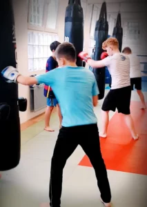 Mehrere Jugendliche machen eine Sandsack-Übung im Youngster Boxtraining von Combat Club Cologne