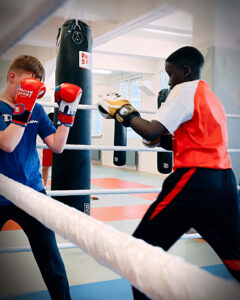 Mehrere Jugendliche machen eine Sandsack-Übung im Youngster Boxtraining von Combat Club Cologne